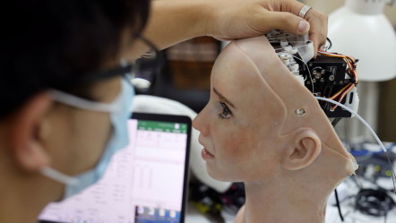 AI: An engineer adjusts the head of the robot Grace.