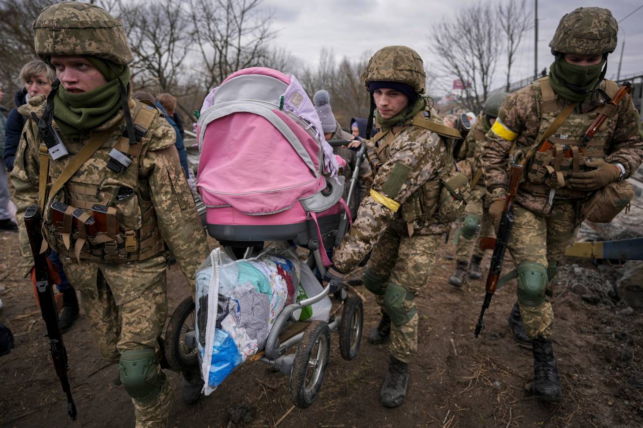 Ukrainian soldiers carry a baby stroller during the evacuation from Irbin on Saturday.