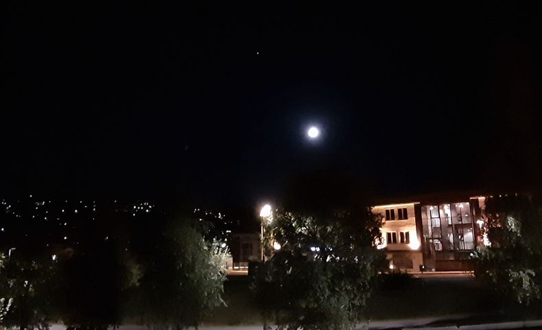 Night sky in Oslo, where the moon and Jupiter appear over the rooftops.