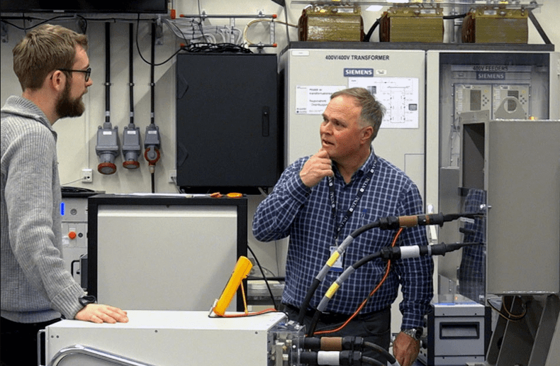 Professor Arne Nesvin supervised Ihiya's PhD work.  Here he discusses troubleshooting with master students in the SmartGrid Lab.